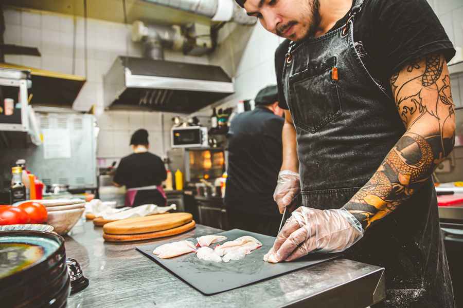 sushikok på en restaurant skærer fisk til fremstilling af sashimi
